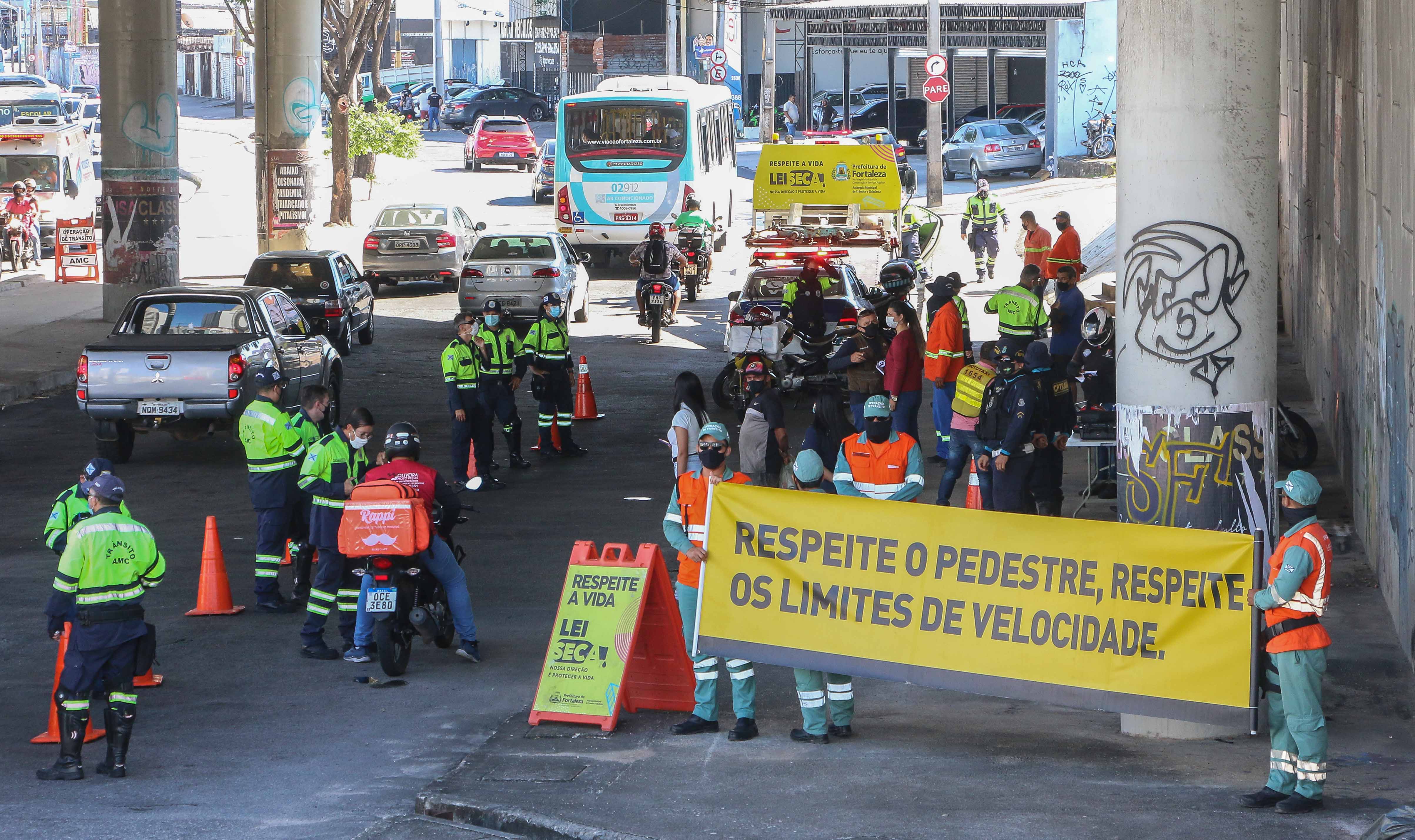 a imagem mostra carros, motocicletas e agentes de trânsito parados em uma blitz embaixo de uma viaduto